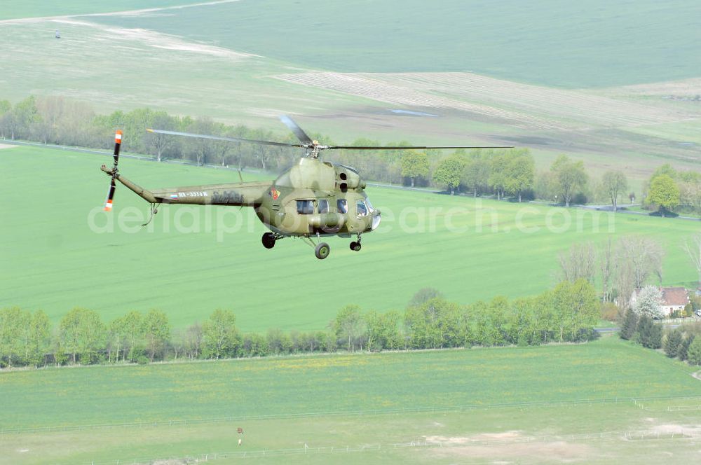 Finow from the bird's eye view: MI-2 Helikopter in Bemalung der ehemaligen NVA-Luftstreitkräfte (Nationale Volksarmee) der DDR mit noch am Rumpf sichtbarer taktischer Nummer der Bundeswehr im Anflug auf den Flugplatz Finow / Eberswalde zum historischen Oldtimertreffen auf dem Freigelände der Luftfahrthistorischen Sammlung. Das Luftfahrzeug fliegt heute unter der russischen Kennung RA-3314 K.