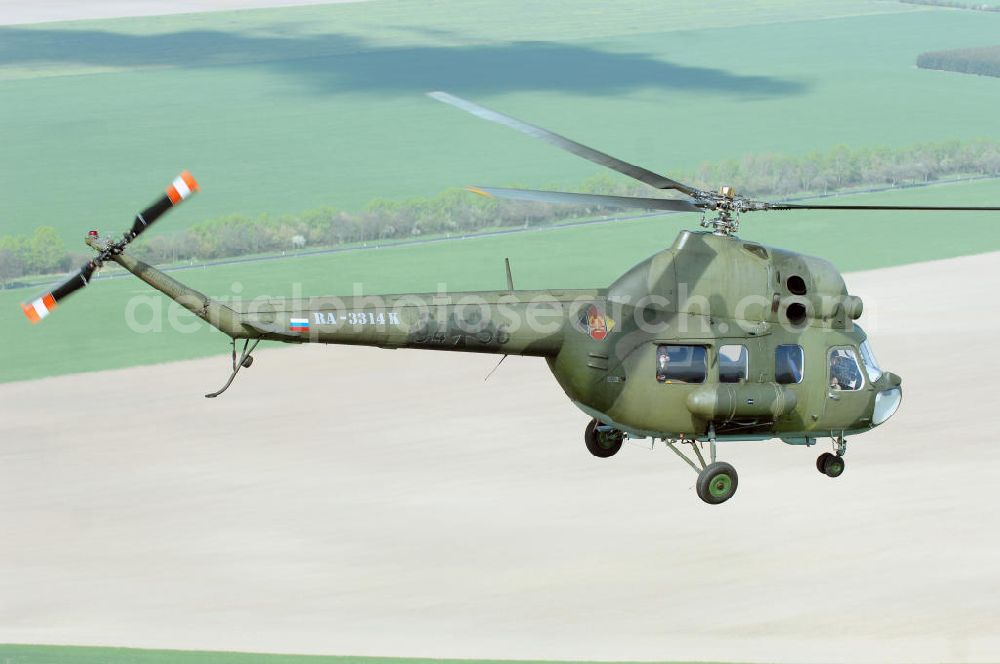 Aerial photograph Finow - MI-2 Helikopter in Bemalung der ehemaligen NVA-Luftstreitkräfte (Nationale Volksarmee) der DDR mit noch am Rumpf sichtbarer taktischer Nummer der Bundeswehr im Anflug auf den Flugplatz Finow / Eberswalde zum historischen Oldtimertreffen auf dem Freigelände der Luftfahrthistorischen Sammlung. Das Luftfahrzeug fliegt heute unter der russischen Kennung RA-3314 K.