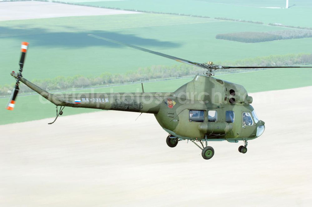 Finow from above - MI-2 Helikopter in Bemalung der ehemaligen NVA-Luftstreitkräfte (Nationale Volksarmee) der DDR mit noch am Rumpf sichtbarer taktischer Nummer der Bundeswehr im Anflug auf den Flugplatz Finow / Eberswalde zum historischen Oldtimertreffen auf dem Freigelände der Luftfahrthistorischen Sammlung. Das Luftfahrzeug fliegt heute unter der russischen Kennung RA-3314 K.