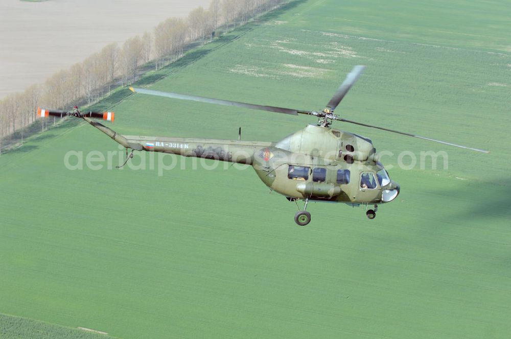 Aerial photograph Finow - MI-2 Helikopter in Bemalung der ehemaligen NVA-Luftstreitkräfte (Nationale Volksarmee) der DDR mit noch am Rumpf sichtbarer taktischer Nummer der Bundeswehr im Anflug auf den Flugplatz Finow / Eberswalde zum historischen Oldtimertreffen auf dem Freigelände der Luftfahrthistorischen Sammlung. Das Luftfahrzeug fliegt heute unter der russischen Kennung RA-3314 K.