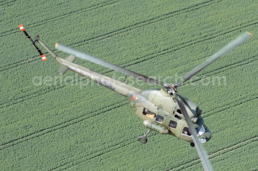 Aerial photograph Finow - MI-2 Helikopter in Bemalung der ehemaligen NVA-Luftstreitkräfte (Nationale Volksarmee) der DDR mit noch am Rumpf sichtbarer taktischer Nummer der Bundeswehr im Anflug auf den Flugplatz Finow / Eberswalde zum historischen Oldtimertreffen auf dem Freigelände der Luftfahrthistorischen Sammlung. Das Luftfahrzeug fliegt heute unter der russischen Kennung RA-3314 K.