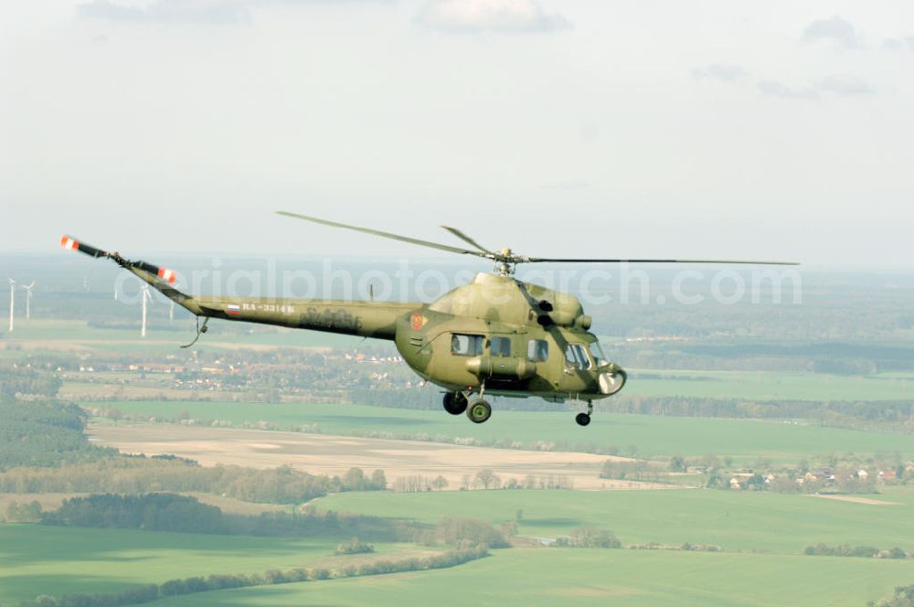 Aerial photograph Finow - MI-2 Helikopter in Bemalung der ehemaligen NVA-Luftstreitkräfte (Nationale Volksarmee) der DDR mit noch am Rumpf sichtbarer taktischer Nummer der Bundeswehr im Anflug auf den Flugplatz Finow / Eberswalde zum historischen Oldtimertreffen auf dem Freigelände der Luftfahrthistorischen Sammlung. Das Luftfahrzeug fliegt heute unter der russischen Kennung RA-3314 K.