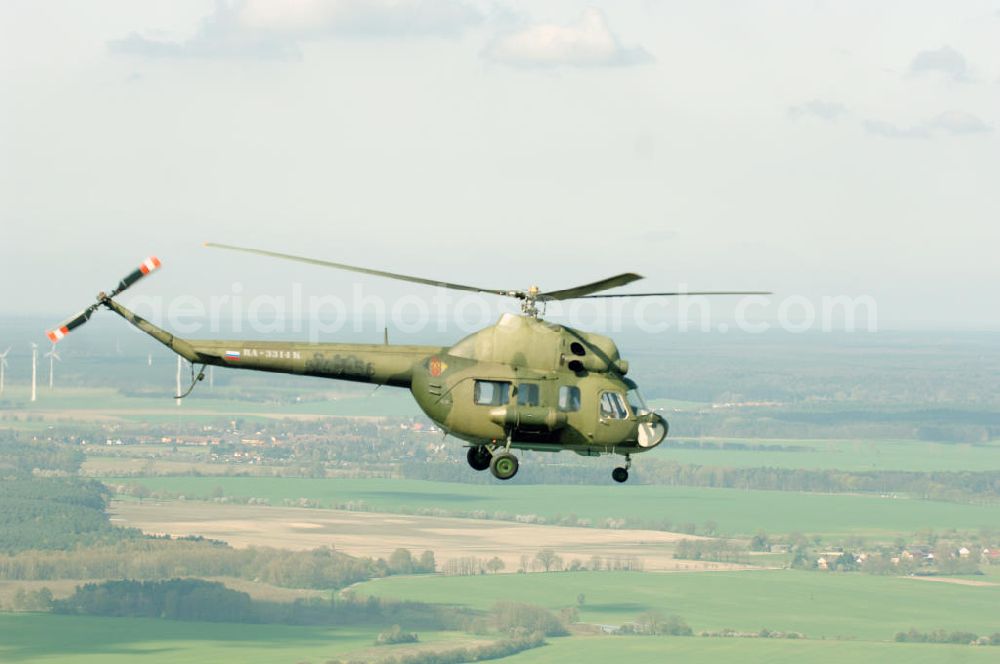 Finow from above - MI-2 Helikopter in Bemalung der ehemaligen NVA-Luftstreitkräfte (Nationale Volksarmee) der DDR mit noch am Rumpf sichtbarer taktischer Nummer der Bundeswehr im Anflug auf den Flugplatz Finow / Eberswalde zum historischen Oldtimertreffen auf dem Freigelände der Luftfahrthistorischen Sammlung. Das Luftfahrzeug fliegt heute unter der russischen Kennung RA-3314 K.