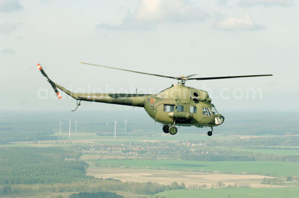 Finow from the bird's eye view: MI-2 Helikopter in Bemalung der ehemaligen NVA-Luftstreitkräfte (Nationale Volksarmee) der DDR mit noch am Rumpf sichtbarer taktischer Nummer der Bundeswehr im Anflug auf den Flugplatz Finow / Eberswalde zum historischen Oldtimertreffen auf dem Freigelände der Luftfahrthistorischen Sammlung. Das Luftfahrzeug fliegt heute unter der russischen Kennung RA-3314 K.