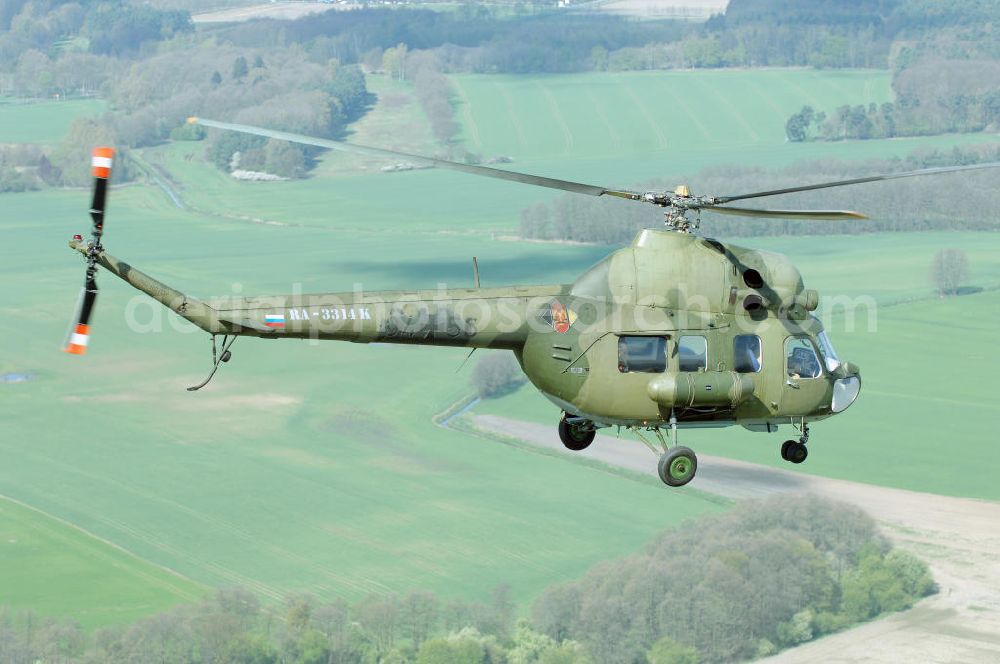 Aerial photograph Finow - MI-2 Helikopter in Bemalung der ehemaligen NVA-Luftstreitkräfte (Nationale Volksarmee) der DDR mit noch am Rumpf sichtbarer taktischer Nummer der Bundeswehr im Anflug auf den Flugplatz Finow / Eberswalde zum historischen Oldtimertreffen auf dem Freigelände der Luftfahrthistorischen Sammlung. Das Luftfahrzeug fliegt heute unter der russischen Kennung RA-3314 K.