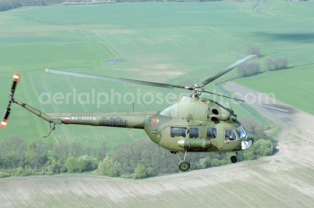 Finow from the bird's eye view: MI-2 Helikopter in Bemalung der ehemaligen NVA-Luftstreitkräfte (Nationale Volksarmee) der DDR mit noch am Rumpf sichtbarer taktischer Nummer der Bundeswehr im Anflug auf den Flugplatz Finow / Eberswalde zum historischen Oldtimertreffen auf dem Freigelände der Luftfahrthistorischen Sammlung. Das Luftfahrzeug fliegt heute unter der russischen Kennung RA-3314 K.