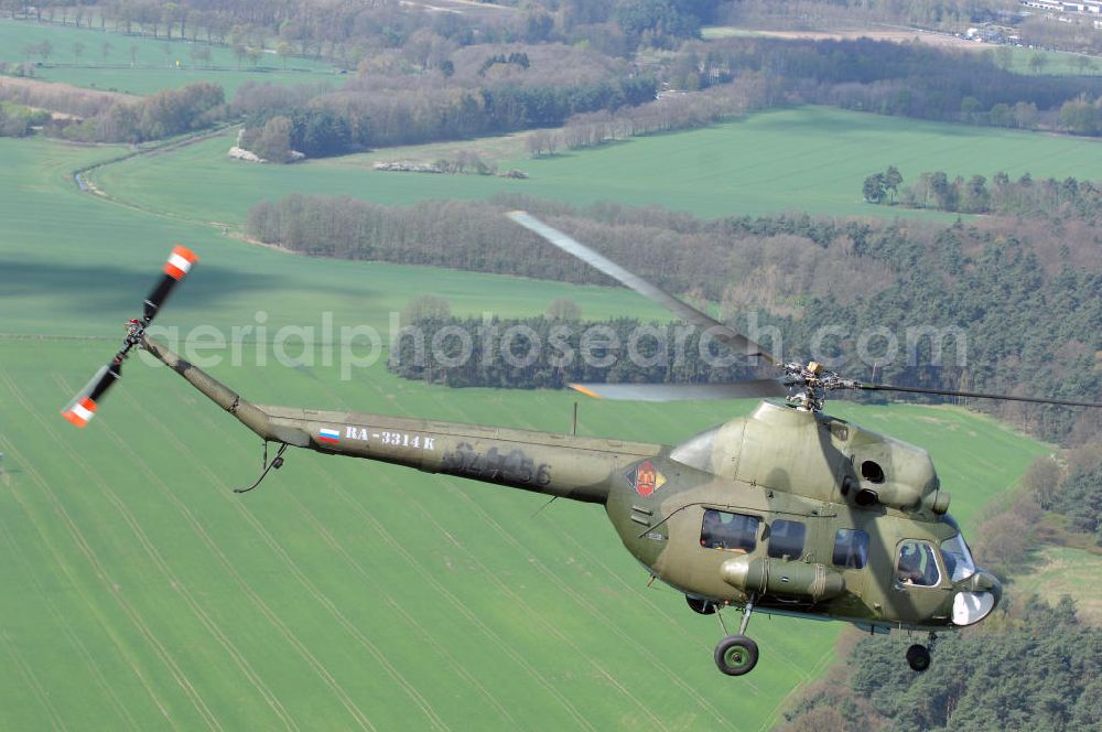 Aerial image Finow - MI-2 Helikopter in Bemalung der ehemaligen NVA-Luftstreitkräfte (Nationale Volksarmee) der DDR mit noch am Rumpf sichtbarer taktischer Nummer der Bundeswehr im Anflug auf den Flugplatz Finow / Eberswalde zum historischen Oldtimertreffen auf dem Freigelände der Luftfahrthistorischen Sammlung. Das Luftfahrzeug fliegt heute unter der russischen Kennung RA-3314 K.