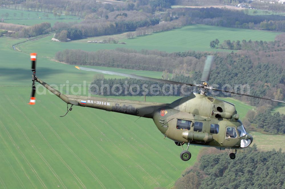 Aerial photograph Finow - MI-2 Helikopter in Bemalung der ehemaligen NVA-Luftstreitkräfte (Nationale Volksarmee) der DDR mit noch am Rumpf sichtbarer taktischer Nummer der Bundeswehr im Anflug auf den Flugplatz Finow / Eberswalde zum historischen Oldtimertreffen auf dem Freigelände der Luftfahrthistorischen Sammlung. Das Luftfahrzeug fliegt heute unter der russischen Kennung RA-3314 K.