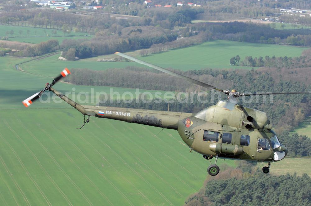 Finow from above - MI-2 Helikopter in Bemalung der ehemaligen NVA-Luftstreitkräfte (Nationale Volksarmee) der DDR mit noch am Rumpf sichtbarer taktischer Nummer der Bundeswehr im Anflug auf den Flugplatz Finow / Eberswalde zum historischen Oldtimertreffen auf dem Freigelände der Luftfahrthistorischen Sammlung. Das Luftfahrzeug fliegt heute unter der russischen Kennung RA-3314 K.