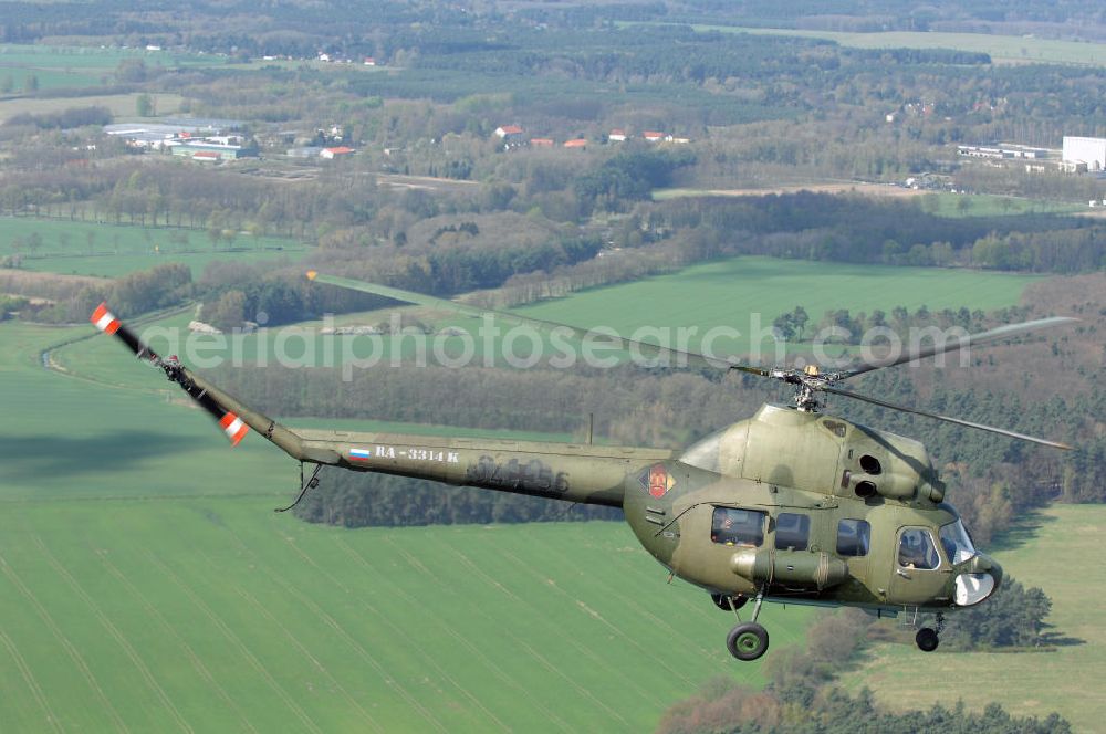 Finow from the bird's eye view: MI-2 Helikopter in Bemalung der ehemaligen NVA-Luftstreitkräfte (Nationale Volksarmee) der DDR mit noch am Rumpf sichtbarer taktischer Nummer der Bundeswehr im Anflug auf den Flugplatz Finow / Eberswalde zum historischen Oldtimertreffen auf dem Freigelände der Luftfahrthistorischen Sammlung. Das Luftfahrzeug fliegt heute unter der russischen Kennung RA-3314 K.