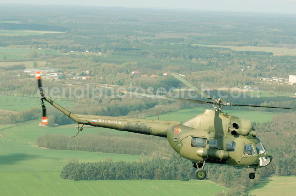 Aerial image Finow - MI-2 Helikopter in Bemalung der ehemaligen NVA-Luftstreitkräfte (Nationale Volksarmee) der DDR mit noch am Rumpf sichtbarer taktischer Nummer der Bundeswehr im Anflug auf den Flugplatz Finow / Eberswalde zum historischen Oldtimertreffen auf dem Freigelände der Luftfahrthistorischen Sammlung. Das Luftfahrzeug fliegt heute unter der russischen Kennung RA-3314 K.