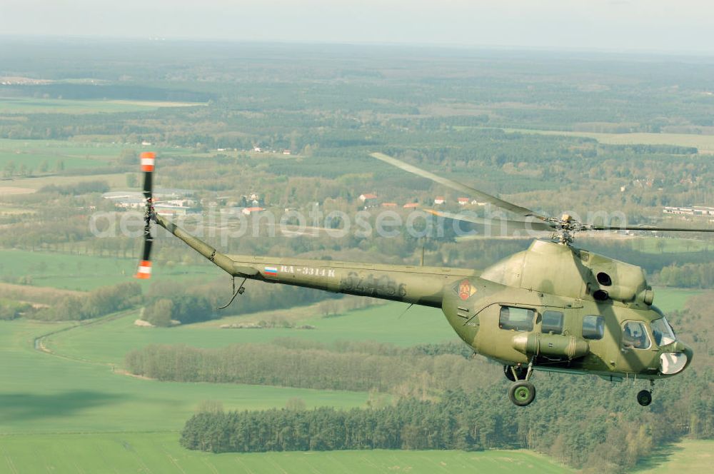 Aerial photograph Finow - MI-2 Helikopter in Bemalung der ehemaligen NVA-Luftstreitkräfte (Nationale Volksarmee) der DDR mit noch am Rumpf sichtbarer taktischer Nummer der Bundeswehr im Anflug auf den Flugplatz Finow / Eberswalde zum historischen Oldtimertreffen auf dem Freigelände der Luftfahrthistorischen Sammlung. Das Luftfahrzeug fliegt heute unter der russischen Kennung RA-3314 K.