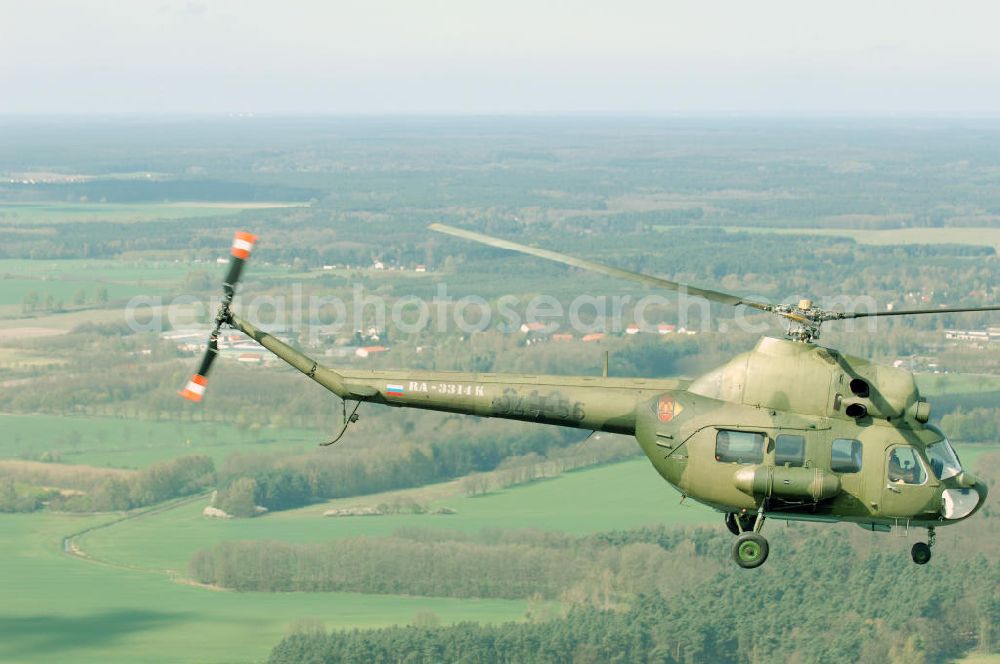 Finow from above - MI-2 Helikopter in Bemalung der ehemaligen NVA-Luftstreitkräfte (Nationale Volksarmee) der DDR mit noch am Rumpf sichtbarer taktischer Nummer der Bundeswehr im Anflug auf den Flugplatz Finow / Eberswalde zum historischen Oldtimertreffen auf dem Freigelände der Luftfahrthistorischen Sammlung. Das Luftfahrzeug fliegt heute unter der russischen Kennung RA-3314 K.