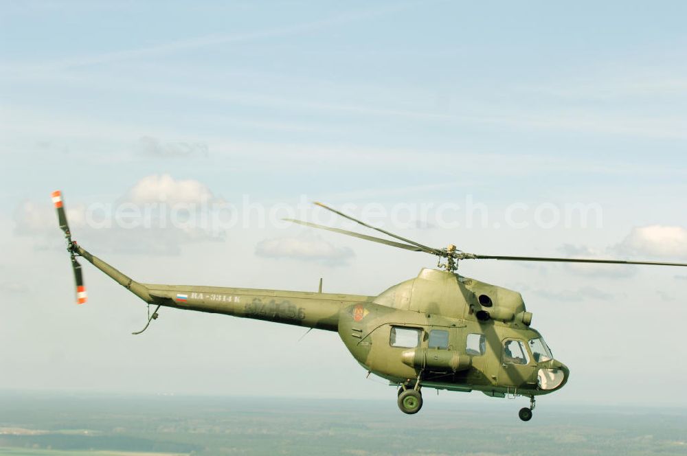 Finow from the bird's eye view: MI-2 Helikopter in Bemalung der ehemaligen NVA-Luftstreitkräfte (Nationale Volksarmee) der DDR mit noch am Rumpf sichtbarer taktischer Nummer der Bundeswehr im Anflug auf den Flugplatz Finow / Eberswalde zum historischen Oldtimertreffen auf dem Freigelände der Luftfahrthistorischen Sammlung. Das Luftfahrzeug fliegt heute unter der russischen Kennung RA-3314 K.