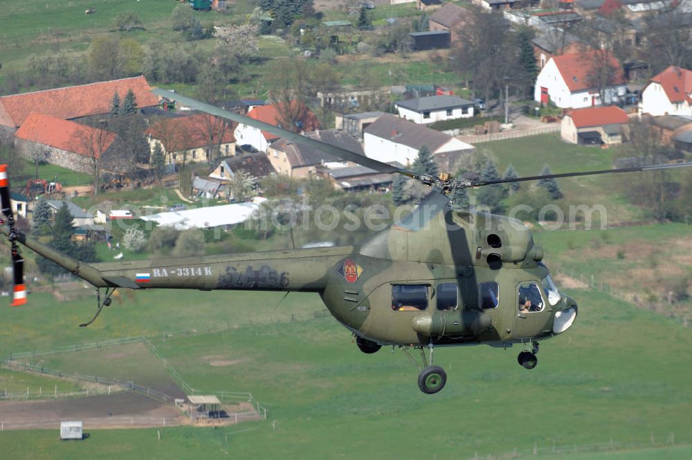 Aerial image Finow - MI-2 Helikopter in Bemalung der ehemaligen NVA-Luftstreitkräfte (Nationale Volksarmee) der DDR mit noch am Rumpf sichtbarer taktischer Nummer der Bundeswehr im Anflug auf den Flugplatz Finow / Eberswalde zum historischen Oldtimertreffen auf dem Freigelände der Luftfahrthistorischen Sammlung. Das Luftfahrzeug fliegt heute unter der russischen Kennung RA-3314 K.