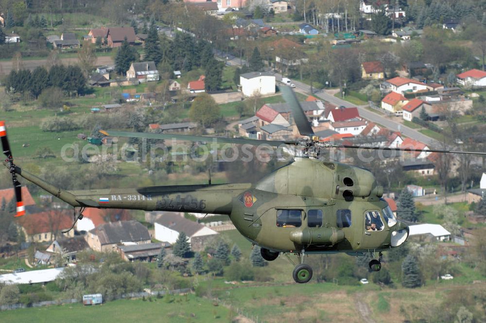 Aerial photograph Finow - MI-2 Helikopter in Bemalung der ehemaligen NVA-Luftstreitkräfte (Nationale Volksarmee) der DDR mit noch am Rumpf sichtbarer taktischer Nummer der Bundeswehr im Anflug auf den Flugplatz Finow / Eberswalde zum historischen Oldtimertreffen auf dem Freigelände der Luftfahrthistorischen Sammlung. Das Luftfahrzeug fliegt heute unter der russischen Kennung RA-3314 K.