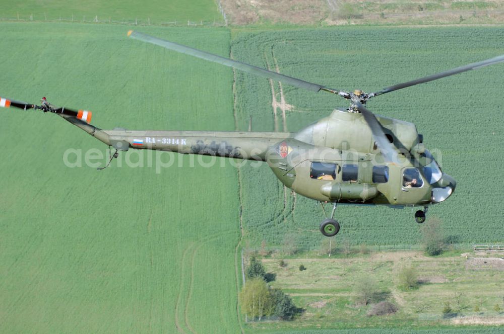 Finow from above - MI-2 Helikopter in Bemalung der ehemaligen NVA-Luftstreitkräfte (Nationale Volksarmee) der DDR mit noch am Rumpf sichtbarer taktischer Nummer der Bundeswehr im Anflug auf den Flugplatz Finow / Eberswalde zum historischen Oldtimertreffen auf dem Freigelände der Luftfahrthistorischen Sammlung. Das Luftfahrzeug fliegt heute unter der russischen Kennung RA-3314 K.