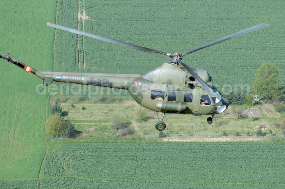 Finow from the bird's eye view: MI-2 Helikopter in Bemalung der ehemaligen NVA-Luftstreitkräfte (Nationale Volksarmee) der DDR mit noch am Rumpf sichtbarer taktischer Nummer der Bundeswehr im Anflug auf den Flugplatz Finow / Eberswalde zum historischen Oldtimertreffen auf dem Freigelände der Luftfahrthistorischen Sammlung. Das Luftfahrzeug fliegt heute unter der russischen Kennung RA-3314 K.