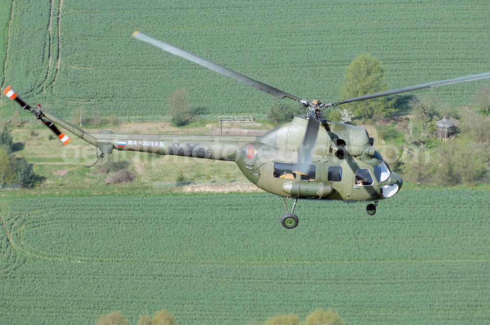 Aerial image Finow - MI-2 Helikopter in Bemalung der ehemaligen NVA-Luftstreitkräfte (Nationale Volksarmee) der DDR mit noch am Rumpf sichtbarer taktischer Nummer der Bundeswehr im Anflug auf den Flugplatz Finow / Eberswalde zum historischen Oldtimertreffen auf dem Freigelände der Luftfahrthistorischen Sammlung. Das Luftfahrzeug fliegt heute unter der russischen Kennung RA-3314 K.