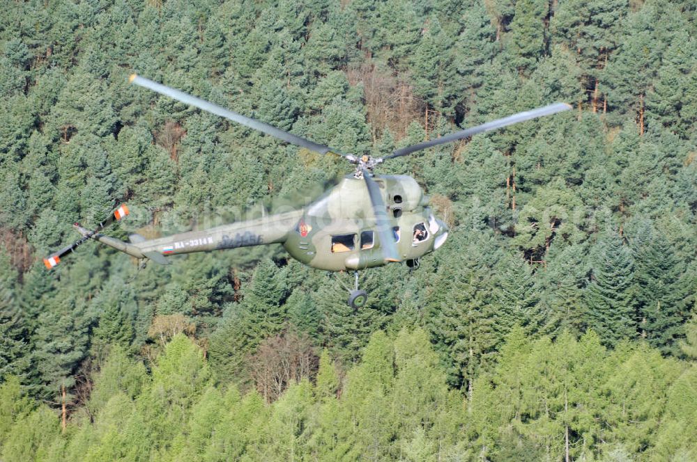 Aerial photograph Finow - MI-2 Helikopter in Bemalung der ehemaligen NVA-Luftstreitkräfte (Nationale Volksarmee) der DDR mit noch am Rumpf sichtbarer taktischer Nummer der Bundeswehr im Anflug auf den Flugplatz Finow / Eberswalde zum historischen Oldtimertreffen auf dem Freigelände der Luftfahrthistorischen Sammlung. Das Luftfahrzeug fliegt heute unter der russischen Kennung RA-3314 K.