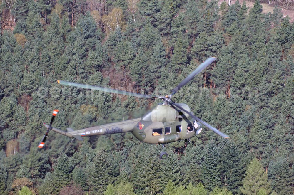 Finow from above - MI-2 Helikopter in Bemalung der ehemaligen NVA-Luftstreitkräfte (Nationale Volksarmee) der DDR mit noch am Rumpf sichtbarer taktischer Nummer der Bundeswehr im Anflug auf den Flugplatz Finow / Eberswalde zum historischen Oldtimertreffen auf dem Freigelände der Luftfahrthistorischen Sammlung. Das Luftfahrzeug fliegt heute unter der russischen Kennung RA-3314 K.