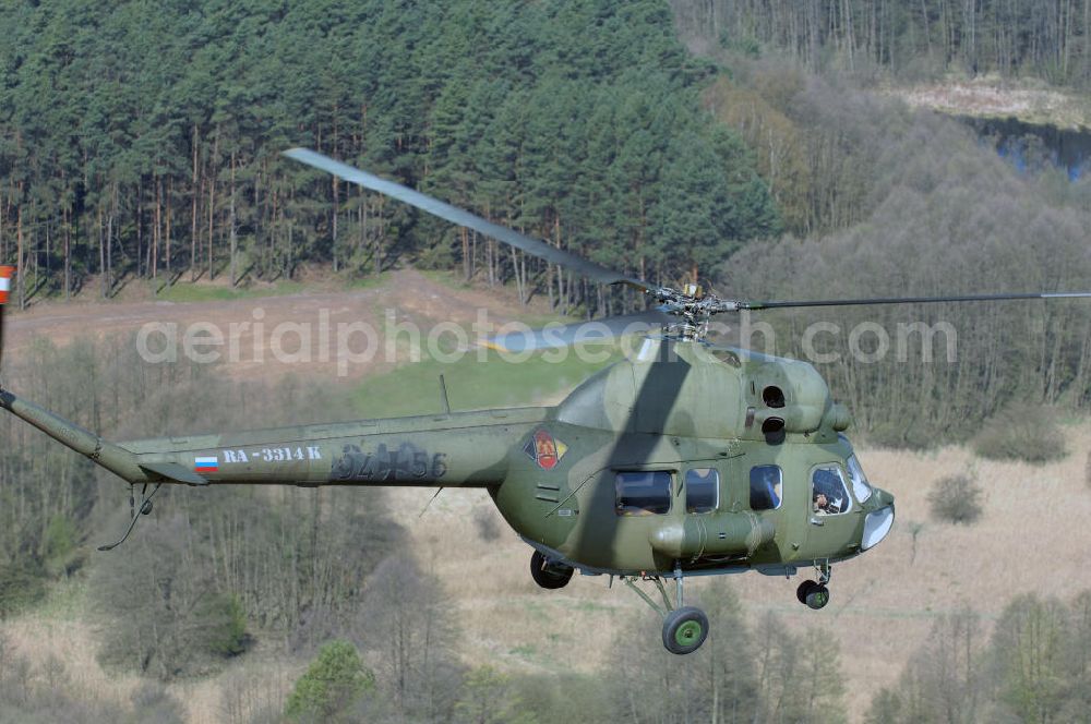 Finow from the bird's eye view: MI-2 Helikopter in Bemalung der ehemaligen NVA-Luftstreitkräfte (Nationale Volksarmee) der DDR mit noch am Rumpf sichtbarer taktischer Nummer der Bundeswehr im Anflug auf den Flugplatz Finow / Eberswalde zum historischen Oldtimertreffen auf dem Freigelände der Luftfahrthistorischen Sammlung. Das Luftfahrzeug fliegt heute unter der russischen Kennung RA-3314 K.