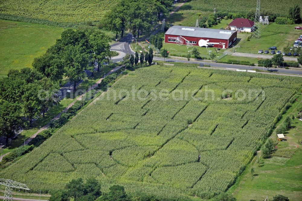 Aerial photograph Storkow - Blick auf das Labyrinth im Maisfeld des MitMachParks IRRLANDIA. Im Hintergrund das Museum des Velodesigners Didi Senft, der mehrere Weltrekorde im Bezug auf den Fahrradbau hält, z.B. das größte Fahrrad der Welt. View of the maze in the corn field of the Event Park IRRLANDIA. In the background, the Museum of the Velodesigners Didi Senft, who holds several world records in relation to the bicycle design, eg the biggest bike in the world.