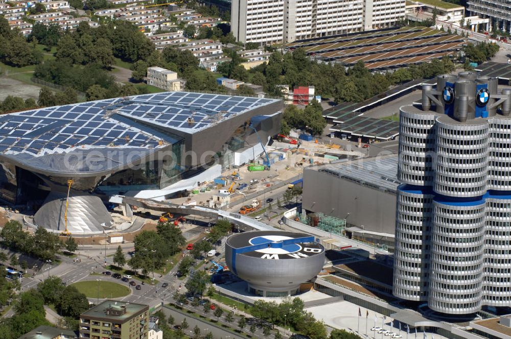 Aerial photograph München - Der BMW Vierzylinder (auch: BMW-Turm, BMW-Hochhaus) ist das Hauptverwaltungsgebäude und Wahrzeichen des Autoherstellers BMW in München. Die BMW Welt wurde von den Architekten Coop Himmelb(l)au für BMW errichtet. Auf dem Dach ist eine Solaranlage mit 800 KW Leistung installiert. Genutzt wird das Gebäude für Ausstellungen rund um das Thema BMW. Weitere Informationen unter: