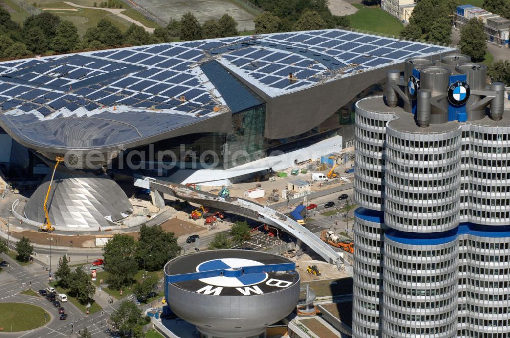 München from above - Der BMW Vierzylinder (auch: BMW-Turm, BMW-Hochhaus) ist das Hauptverwaltungsgebäude und Wahrzeichen des Autoherstellers BMW in München. Die BMW Welt wurde von den Architekten Coop Himmelb(l)au für BMW errichtet. Auf dem Dach ist eine Solaranlage mit 800 KW Leistung installiert. Genutzt wird das Gebäude für Ausstellungen rund um das Thema BMW. Weitere Informationen unter: