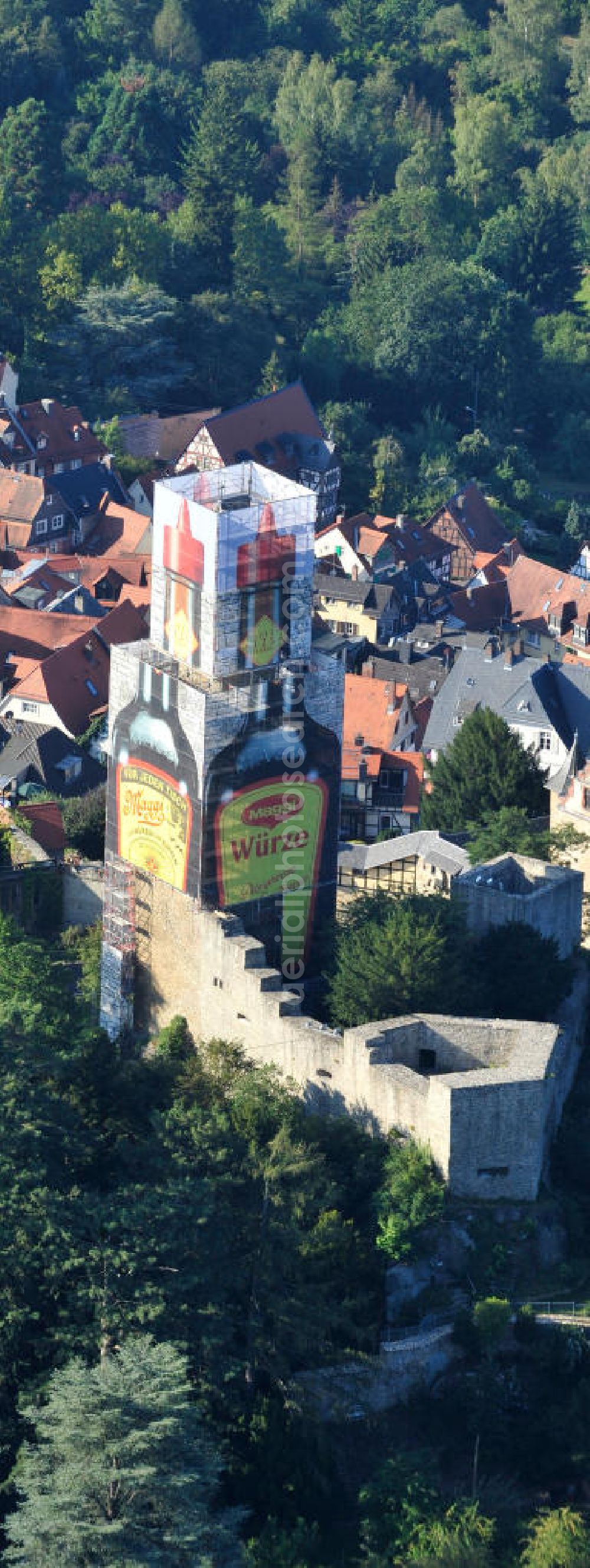 Kronberg im Taunus from above - Blick auf eine Maggiflasche als Großwerbeplakat auf der Einrüstung der Burg Kronberg. Zum 125-jährigen Jubiläum der Maggi-Würzsoße wurde der im Volksmund als Maggi-Flasche bezeichnete Turm des Kronberger Wahrzeichens für drei Monate als Werbeträger genutzt. Die Werbeeinnahmen der NESTLE Gruppe fließen unmittelbar in die Burgsanierung. View a bottle of Maggi at Burg Kronberg.