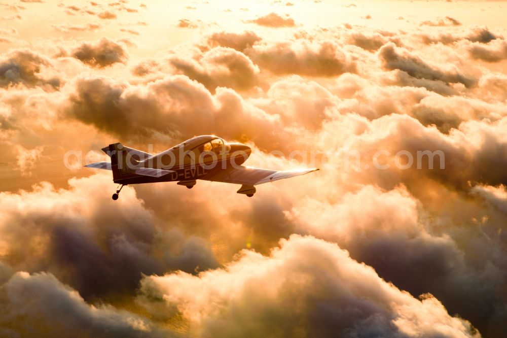 Cuxhaven from the bird's eye view: Motor aircraft and sports aircraft flying above clouds in the evening light of sunset over the airspace in Cuxhaven in the federal state of Lower Saxony, Germany