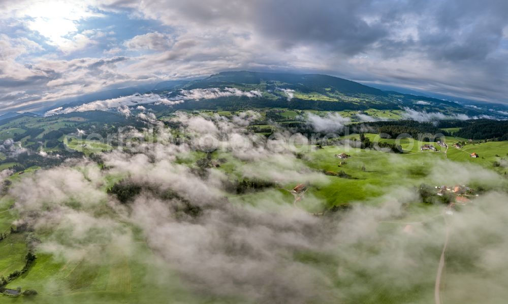 Irsengund from above - Weather related fog banks and cloud layer over forest and meadow landscape in Irsengund allgaeu in the state Bavaria, Germany