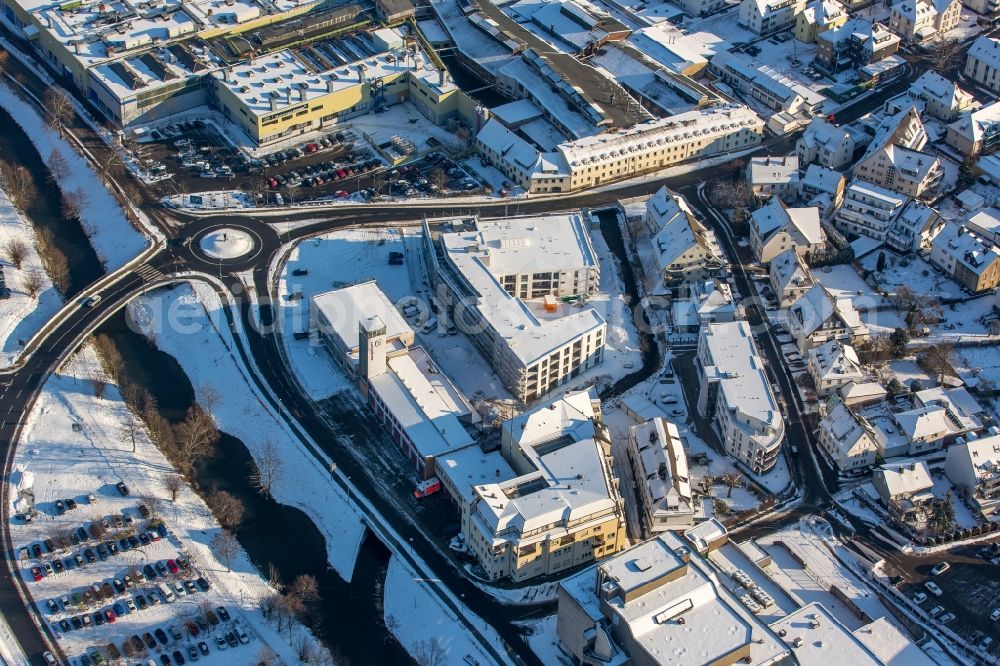 Aerial image Meschede - Winterly snowy building of the retirement home Rinschen Park of the company Siedlungs- und Baugenossenschaft Meschede eG aswell as the building complex of the volunteer fire brigade of Meschede beneath the roads Fritz-Honsel-Strasse and Muehlenweg and the river Ruhr in Meschede in the state North Rhine-Westphalia