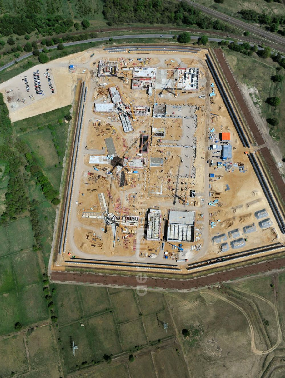 Aerial photograph Großbeeren - Baustelle vom Neubau der Justizvollzugsanstalt JVA Heidering Großbeeren im Landkreis Teltow-Fläming in Brandenburg durch die Senatsverwaltung für Justiz. Der Neubau der Haftanstalt in Großbeeren wird nur elektrisch und mit einem Erdwall gesichert statt mit einer koventionellen Gefängnismauer. Die Projektentwurf erfolgte durch das Architekturbüro Hohensinn. Ausführende Baufirmen sind die Bleck & Söhne Hoch- und Tiefbau GmbH & Co. KG, sowie die Schälerbau Berlin. Construction site of the new penal institution Heidering Grossbeeren.