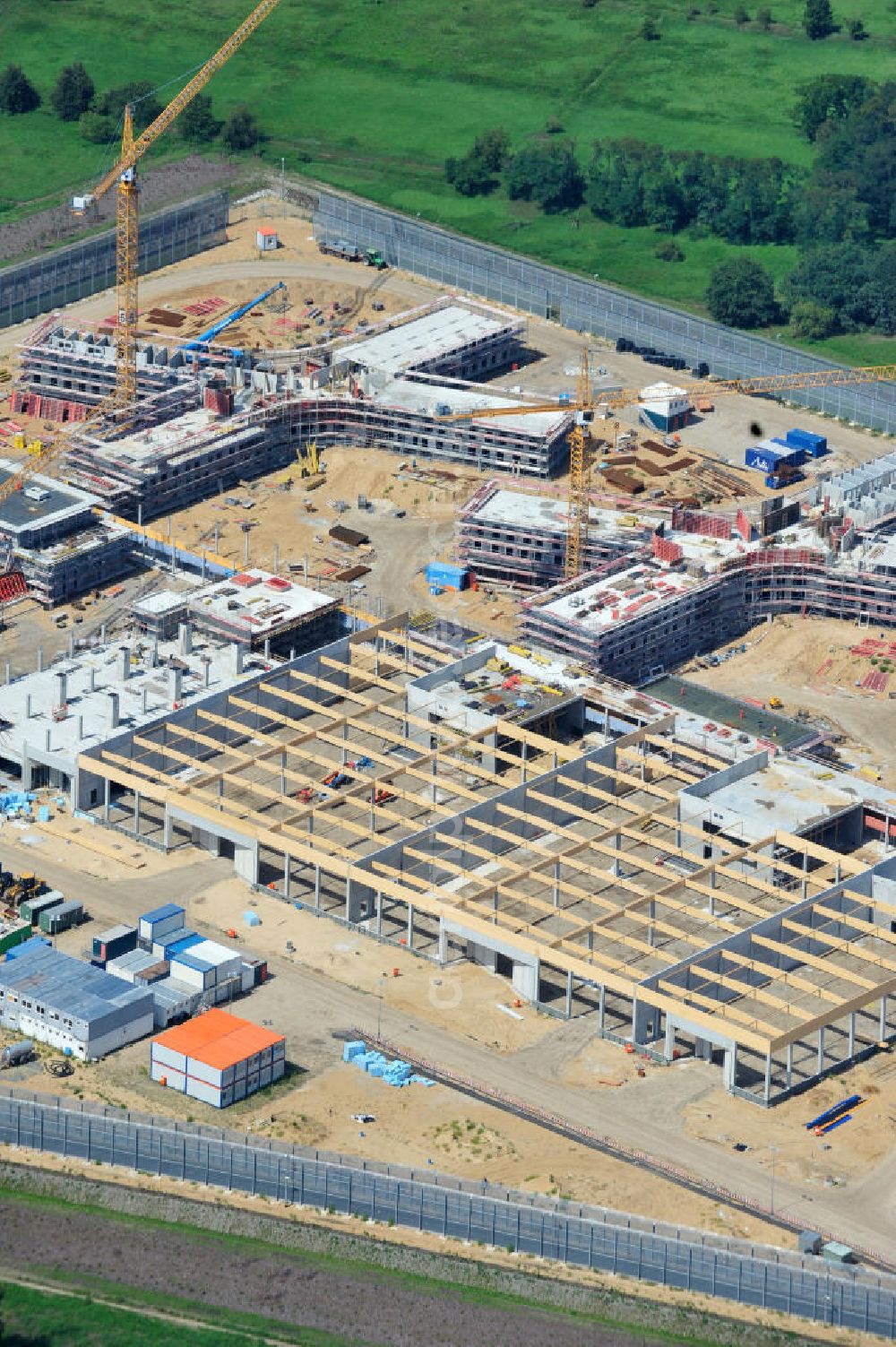 Großbeeren from the bird's eye view: Baustelle vom Neubau der Justizvollzugsanstalt JVA Heidering Großbeeren im Landkreis Teltow-Fläming in Brandenburg durch die Senatsverwaltung für Justiz. Der Neubau der Haftanstalt in Großbeeren wird nur elektrisch und mit einem Erdwall gesichert statt mit einer koventionellen Gefängnismauer. Die Projektentwurf erfolgte durch das Architekturbüro Hohensinn. Ausführende Baufirmen sind die Bleck & Söhne Hoch- und Tiefbau GmbH & Co. KG, sowie die Schälerbau Berlin. Construction site of the new penal institution Heidering Grossbeeren.