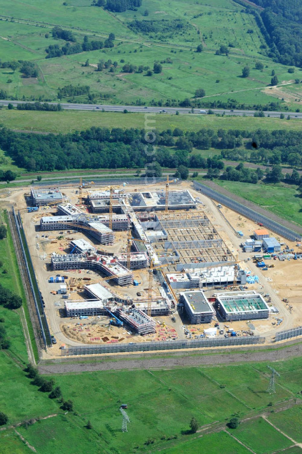 Großbeeren from the bird's eye view: Baustelle vom Neubau der Justizvollzugsanstalt JVA Heidering Großbeeren im Landkreis Teltow-Fläming in Brandenburg durch die Senatsverwaltung für Justiz. Der Neubau der Haftanstalt in Großbeeren wird nur elektrisch und mit einem Erdwall gesichert statt mit einer koventionellen Gefängnismauer. Die Projektentwurf erfolgte durch das Architekturbüro Hohensinn. Ausführende Baufirmen sind die Bleck & Söhne Hoch- und Tiefbau GmbH & Co. KG, sowie die Schälerbau Berlin. Construction site of the new penal institution Heidering Grossbeeren.