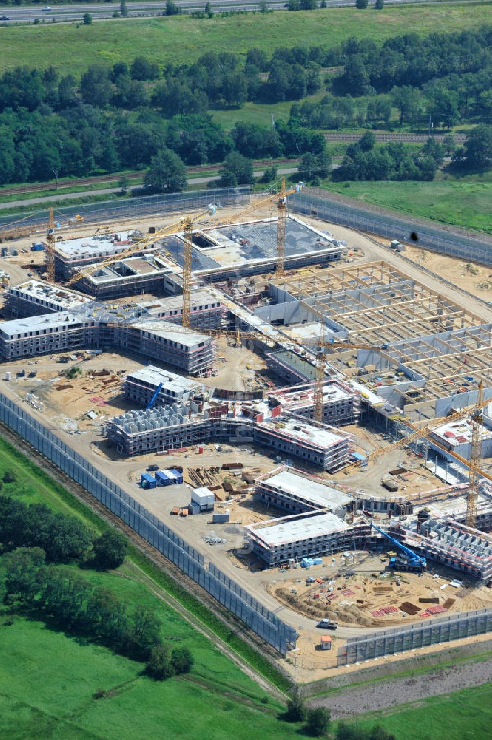 Aerial photograph Großbeeren - Baustelle vom Neubau der Justizvollzugsanstalt JVA Heidering Großbeeren im Landkreis Teltow-Fläming in Brandenburg durch die Senatsverwaltung für Justiz. Der Neubau der Haftanstalt in Großbeeren wird nur elektrisch und mit einem Erdwall gesichert statt mit einer koventionellen Gefängnismauer. Die Projektentwurf erfolgte durch das Architekturbüro Hohensinn. Ausführende Baufirmen sind die Bleck & Söhne Hoch- und Tiefbau GmbH & Co. KG, sowie die Schälerbau Berlin. Construction site of the new penal institution Heidering Grossbeeren.