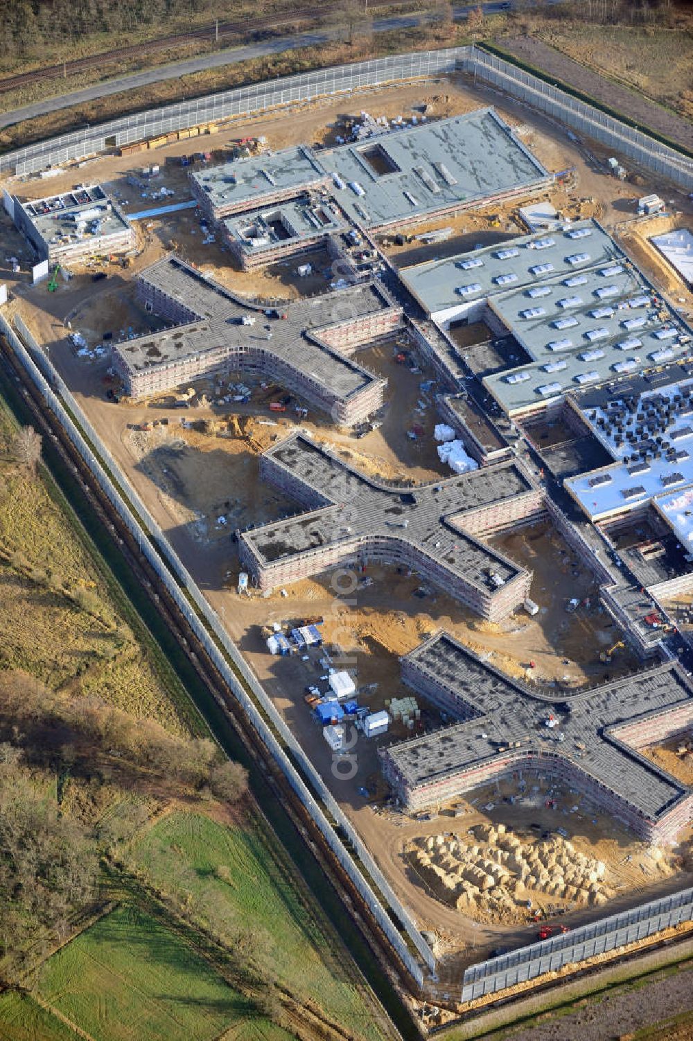 Aerial image Großbeeren - Baustelle vom Neubau der Justizvollzugsanstalt JVA Heidering Großbeeren im Landkreis Teltow-Fläming in Brandenburg durch die Senatsverwaltung für Justiz. Der Neubau der Haftanstalt in Großbeeren wird nur elektrisch und mit einem Erdwall gesichert statt mit einer koventionellen Gefängnismauer. Die Projektentwurf erfolgte durch das Architekturbüro Hohensinn. Ausführende Baufirmen sind die Bleck & Söhne Hoch- und Tiefbau GmbH & Co. KG, sowie die Schälerbau Berlin. Construction site of the new penal institution Heidering Grossbeeren.