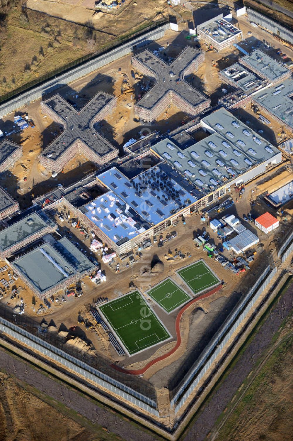 Großbeeren from above - Baustelle vom Neubau der Justizvollzugsanstalt JVA Heidering Großbeeren im Landkreis Teltow-Fläming in Brandenburg durch die Senatsverwaltung für Justiz. Der Neubau der Haftanstalt in Großbeeren wird nur elektrisch und mit einem Erdwall gesichert statt mit einer koventionellen Gefängnismauer. Die Projektentwurf erfolgte durch das Architekturbüro Hohensinn. Ausführende Baufirmen sind die Bleck & Söhne Hoch- und Tiefbau GmbH & Co. KG, sowie die Schälerbau Berlin. Construction site of the new penal institution Heidering Grossbeeren.