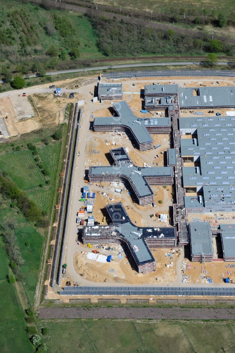 Aerial photograph Großbeeren - Baustelle vom Neubau der Justizvollzugsanstalt JVA Heidering Großbeeren im Landkreis Teltow-Fläming in Brandenburg durch die Senatsverwaltung für Justiz. Der Neubau der Haftanstalt in Großbeeren wird nur elektrisch und mit einem Erdwall gesichert statt mit einer koventionellen Gefängnismauer. Die Projektentwurf erfolgte durch das Architekturbüro Hohensinn. Ausführende Baufirmen sind die Bleck & Söhne Hoch- und Tiefbau GmbH & Co. KG, sowie die Schälerbau Berlin. Construction site of the new penal institution Heidering Grossbeeren.