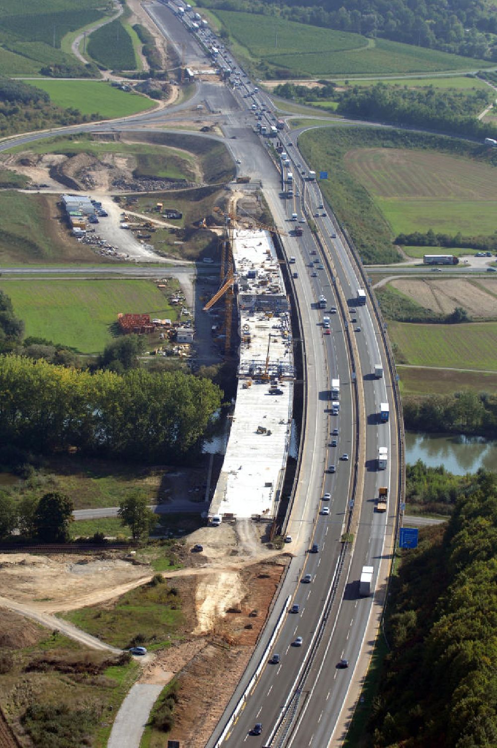 Aerial photograph Randersacker - Blick auf den Neubau der Mainbrücke der A3 bei Ran dersacker und Würzburg über den Main. Die Mainbrücke Ran dersacker ist eine 540 m lange Brücke der Autobahn 3. Das Bauwerk liegt zwischen den Autobahnanschlussstellen Würzburg-Heidingsfeld und Würzburg-Ran dersacker. Es überspannt südlich von Würzburg bei Ran dersacker in einer Höhe von ungefähr 20 m den Main. Das Bauunternehmen DYWIDAG ist für dieses Projekt zuständig. DYWIDAG wurde 1865 als Lang & Cie. Betonwarenfabrik gegründet und gehörte mit zu den großen deutschen Baukonzernen. Die Gründungsväter des Unternehmens waren Heinrich Lang und Wilhelm Gustav Dyckerhoff. Kontakt: DYWIDAG Bau GmbH, Mies-van-der-Rohe-Straße 6, 80807 München, Tel. +49 (0)89 360 555 2422