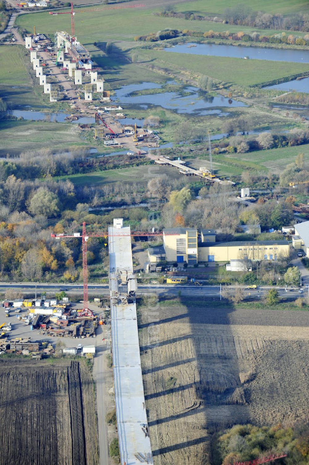 Aerial photograph Rattmannsdorf - Blick auf die Vorschub- Bauarbeiten an der Saale-Elster-Talbrücke zwischen Ammendorf und Schkopau. Das Beton- Viadukt mit insgesamt 8, 5 Kilometern Länge wird teilweise mit großen Baugerüsten in so genannter Vor-Kopf-Bauweise errichtet. Die ICE - Neubaustrecke im Projekt VDE 8 Nürnberg-Berlin der Deutschen Bahn und der DEGES soll 2015 in Betrieb gehen und wird das bisher längste Brückenbauwerk Deutschlands sein. Bauausführende Firmen sind die Hochtief Construction AG, Adam Hörnig, Gerdum und Breuer; Franki Grundbau; Doka Schalungstechniker; BBV Vorspanntechnik; Röro Traggerüstsysteme; Oevermann Hoch- und Tiefbau, Teupe & Söhne Gerüstbau GmbH, Alpine Bau, Kann Baustoffe und Arcelormittal. Die Bauüberwachung erfolgt durch das Ingenieurbüro Schüßler Plan. View of the construction of the Saale-Elster Viaduct between Ammandorf and Schkopau in Saxony Anhalt.