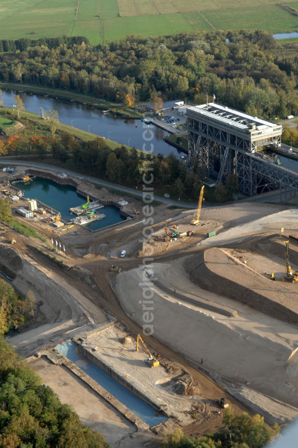 Niederfinow from the bird's eye view: Das Wasserstraßen-Neubauamt Berlin den Bauauftrag für den Neubau des Schiffshebewerkes Niederfinow Nord vergeben. Der Zuschlag wurde auf das Angebot der Bietergemeinschaft Neues Schiffshebewerk Niederfinow unter Federführung der Bilfinger Berger AG erteilt. Der Bietergemeinschaft gehören weiter: die DSD Brückenbau GmbH, die Johann Bunte Bauunternehmung GmbH & Co. KG und die Siemag GmbH an. Die geplante Bauzeit für das neue Schiffshebewerk beträgt fünf Jahre, die Baukosten für die Gesamtanlage liegen bei rd. 285 Mio. Euro und werden durch den Bund finanziert. Seit Mitte Februar 2009 wird die Baugrubenumschließung für das neue Schiffshebewerk hergestellt. Es werden 217 Träger und 214 Zwischenbohlen in den Baugrund eingebracht. Die Träger haben eine Länge von ca. 22m und wiegen einzeln etwa 5,7 Tonnen. Die Rüttelarbeiten für die Baugrube werden voraussichtlich bis Ende April andauern.Mit einem Investitionsvolumen von rd. 285. Mio € entsteht in Niederfinow bis zum Jahr 2014 ein neues Schiffshebewerk der europäischen Wasserstraßenklasse V. Der Neubau ist dringend erforderlich, weil das alte Schiffshebewerk aus dem Jahr 1934 bald das Ende seiner Lebensdauer erreicht hat. Um die Funktion der Havel-Oder-Wasserstraße aufrechtzuerhalten, muss es daher planmäßig durch einen Neubau ersetzt werden.