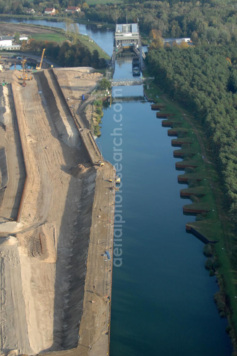 Aerial image Niederfinow - Das Wasserstraßen-Neubauamt Berlin den Bauauftrag für den Neubau des Schiffshebewerkes Niederfinow Nord vergeben. Der Zuschlag wurde auf das Angebot der Bietergemeinschaft Neues Schiffshebewerk Niederfinow unter Federführung der Bilfinger Berger AG erteilt. Der Bietergemeinschaft gehören weiter: die DSD Brückenbau GmbH, die Johann Bunte Bauunternehmung GmbH & Co. KG und die Siemag GmbH an. Die geplante Bauzeit für das neue Schiffshebewerk beträgt fünf Jahre, die Baukosten für die Gesamtanlage liegen bei rd. 285 Mio. Euro und werden durch den Bund finanziert. Seit Mitte Februar 2009 wird die Baugrubenumschließung für das neue Schiffshebewerk hergestellt. Es werden 217 Träger und 214 Zwischenbohlen in den Baugrund eingebracht. Die Träger haben eine Länge von ca. 22m und wiegen einzeln etwa 5,7 Tonnen. Die Rüttelarbeiten für die Baugrube werden voraussichtlich bis Ende April andauern.Mit einem Investitionsvolumen von rd. 285. Mio € entsteht in Niederfinow bis zum Jahr 2014 ein neues Schiffshebewerk der europäischen Wasserstraßenklasse V. Der Neubau ist dringend erforderlich, weil das alte Schiffshebewerk aus dem Jahr 1934 bald das Ende seiner Lebensdauer erreicht hat. Um die Funktion der Havel-Oder-Wasserstraße aufrechtzuerhalten, muss es daher planmäßig durch einen Neubau ersetzt werden.