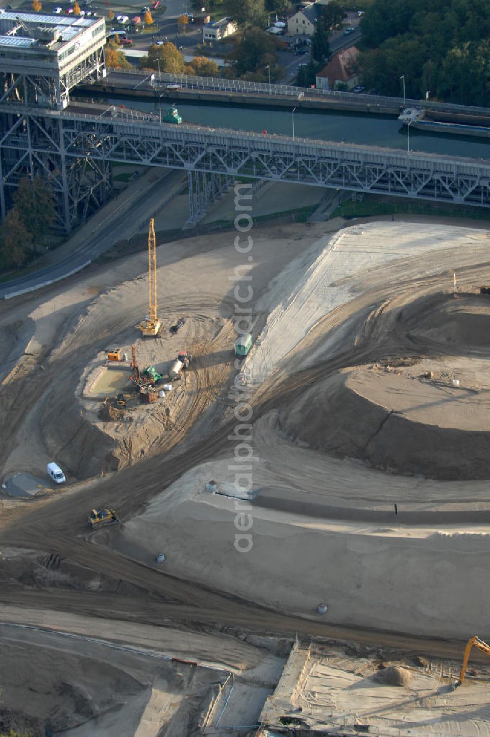 Niederfinow from the bird's eye view: Das Wasserstraßen-Neubauamt Berlin den Bauauftrag für den Neubau des Schiffshebewerkes Niederfinow Nord vergeben. Der Zuschlag wurde auf das Angebot der Bietergemeinschaft Neues Schiffshebewerk Niederfinow unter Federführung der Bilfinger Berger AG erteilt. Der Bietergemeinschaft gehören weiter: die DSD Brückenbau GmbH, die Johann Bunte Bauunternehmung GmbH & Co. KG und die Siemag GmbH an. Die geplante Bauzeit für das neue Schiffshebewerk beträgt fünf Jahre, die Baukosten für die Gesamtanlage liegen bei rd. 285 Mio. Euro und werden durch den Bund finanziert. Seit Mitte Februar 2009 wird die Baugrubenumschließung für das neue Schiffshebewerk hergestellt. Es werden 217 Träger und 214 Zwischenbohlen in den Baugrund eingebracht. Die Träger haben eine Länge von ca. 22m und wiegen einzeln etwa 5,7 Tonnen. Die Rüttelarbeiten für die Baugrube werden voraussichtlich bis Ende April andauern.Mit einem Investitionsvolumen von rd. 285. Mio € entsteht in Niederfinow bis zum Jahr 2014 ein neues Schiffshebewerk der europäischen Wasserstraßenklasse V. Der Neubau ist dringend erforderlich, weil das alte Schiffshebewerk aus dem Jahr 1934 bald das Ende seiner Lebensdauer erreicht hat. Um die Funktion der Havel-Oder-Wasserstraße aufrechtzuerhalten, muss es daher planmäßig durch einen Neubau ersetzt werden.