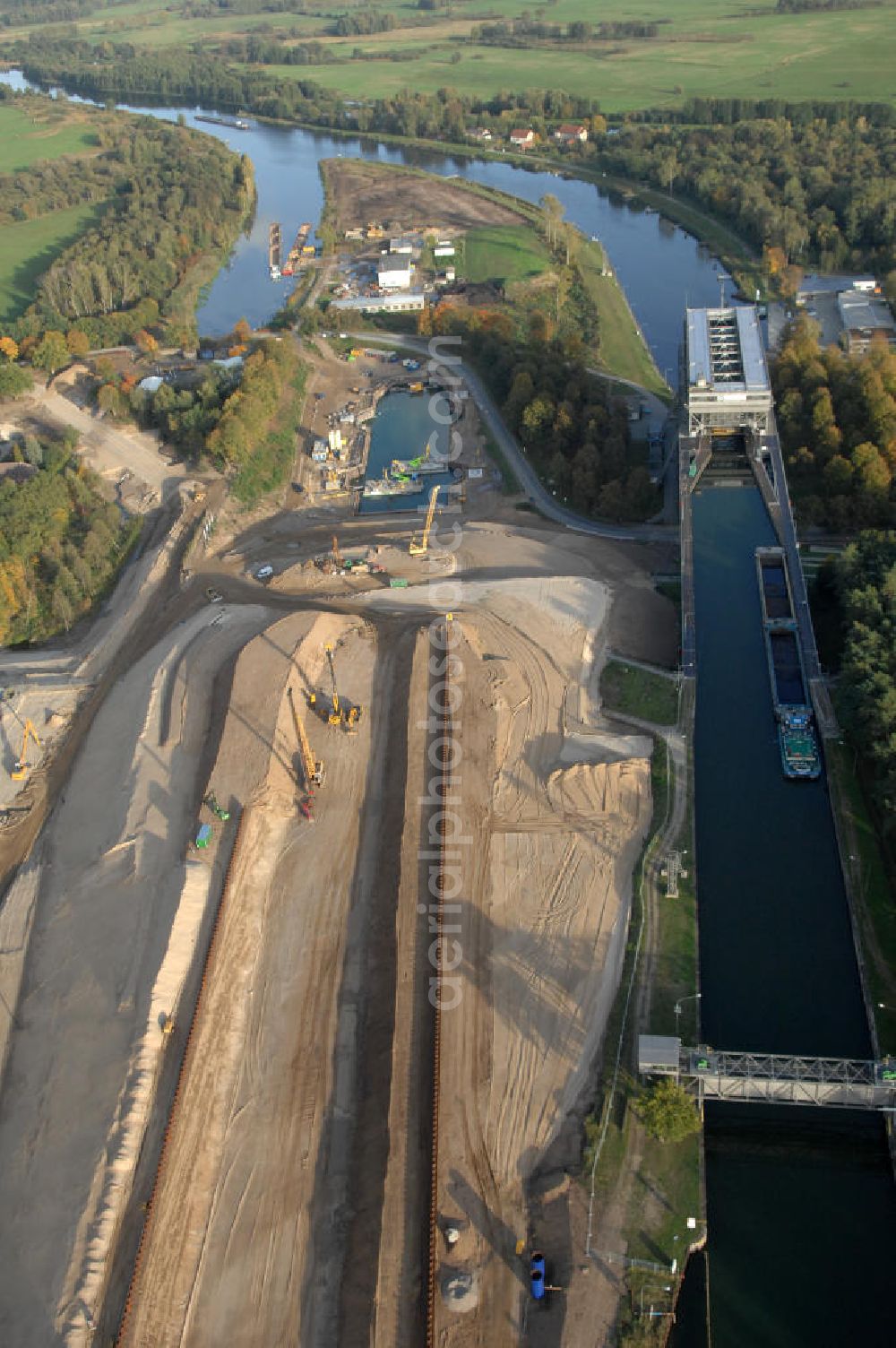 Aerial image Niederfinow - Das Wasserstraßen-Neubauamt Berlin den Bauauftrag für den Neubau des Schiffshebewerkes Niederfinow Nord vergeben. Der Zuschlag wurde auf das Angebot der Bietergemeinschaft Neues Schiffshebewerk Niederfinow unter Federführung der Bilfinger Berger AG erteilt. Der Bietergemeinschaft gehören weiter: die DSD Brückenbau GmbH, die Johann Bunte Bauunternehmung GmbH & Co. KG und die Siemag GmbH an. Die geplante Bauzeit für das neue Schiffshebewerk beträgt fünf Jahre, die Baukosten für die Gesamtanlage liegen bei rd. 285 Mio. Euro und werden durch den Bund finanziert. Seit Mitte Februar 2009 wird die Baugrubenumschließung für das neue Schiffshebewerk hergestellt. Es werden 217 Träger und 214 Zwischenbohlen in den Baugrund eingebracht. Die Träger haben eine Länge von ca. 22m und wiegen einzeln etwa 5,7 Tonnen. Die Rüttelarbeiten für die Baugrube werden voraussichtlich bis Ende April andauern.Mit einem Investitionsvolumen von rd. 285. Mio € entsteht in Niederfinow bis zum Jahr 2014 ein neues Schiffshebewerk der europäischen Wasserstraßenklasse V. Der Neubau ist dringend erforderlich, weil das alte Schiffshebewerk aus dem Jahr 1934 bald das Ende seiner Lebensdauer erreicht hat. Um die Funktion der Havel-Oder-Wasserstraße aufrechtzuerhalten, muss es daher planmäßig durch einen Neubau ersetzt werden.