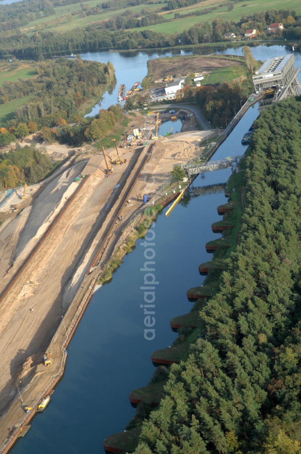 Aerial image Niederfinow - Das Wasserstraßen-Neubauamt Berlin den Bauauftrag für den Neubau des Schiffshebewerkes Niederfinow Nord vergeben. Der Zuschlag wurde auf das Angebot der Bietergemeinschaft Neues Schiffshebewerk Niederfinow unter Federführung der Bilfinger Berger AG erteilt. Der Bietergemeinschaft gehören weiter: die DSD Brückenbau GmbH, die Johann Bunte Bauunternehmung GmbH & Co. KG und die Siemag GmbH an. Die geplante Bauzeit für das neue Schiffshebewerk beträgt fünf Jahre, die Baukosten für die Gesamtanlage liegen bei rd. 285 Mio. Euro und werden durch den Bund finanziert. Seit Mitte Februar 2009 wird die Baugrubenumschließung für das neue Schiffshebewerk hergestellt. Es werden 217 Träger und 214 Zwischenbohlen in den Baugrund eingebracht. Die Träger haben eine Länge von ca. 22m und wiegen einzeln etwa 5,7 Tonnen. Die Rüttelarbeiten für die Baugrube werden voraussichtlich bis Ende April andauern.Mit einem Investitionsvolumen von rd. 285. Mio € entsteht in Niederfinow bis zum Jahr 2014 ein neues Schiffshebewerk der europäischen Wasserstraßenklasse V. Der Neubau ist dringend erforderlich, weil das alte Schiffshebewerk aus dem Jahr 1934 bald das Ende seiner Lebensdauer erreicht hat. Um die Funktion der Havel-Oder-Wasserstraße aufrechtzuerhalten, muss es daher planmäßig durch einen Neubau ersetzt werden.