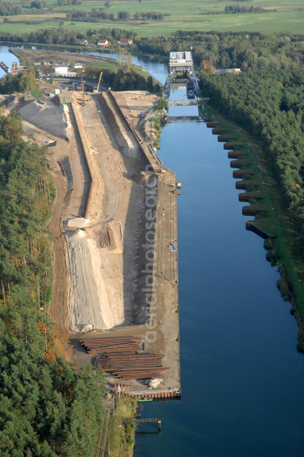 Niederfinow from above - Das Wasserstraßen-Neubauamt Berlin den Bauauftrag für den Neubau des Schiffshebewerkes Niederfinow Nord vergeben. Der Zuschlag wurde auf das Angebot der Bietergemeinschaft Neues Schiffshebewerk Niederfinow unter Federführung der Bilfinger Berger AG erteilt. Der Bietergemeinschaft gehören weiter: die DSD Brückenbau GmbH, die Johann Bunte Bauunternehmung GmbH & Co. KG und die Siemag GmbH an. Die geplante Bauzeit für das neue Schiffshebewerk beträgt fünf Jahre, die Baukosten für die Gesamtanlage liegen bei rd. 285 Mio. Euro und werden durch den Bund finanziert. Seit Mitte Februar 2009 wird die Baugrubenumschließung für das neue Schiffshebewerk hergestellt. Es werden 217 Träger und 214 Zwischenbohlen in den Baugrund eingebracht. Die Träger haben eine Länge von ca. 22m und wiegen einzeln etwa 5,7 Tonnen. Die Rüttelarbeiten für die Baugrube werden voraussichtlich bis Ende April andauern.Mit einem Investitionsvolumen von rd. 285. Mio € entsteht in Niederfinow bis zum Jahr 2014 ein neues Schiffshebewerk der europäischen Wasserstraßenklasse V. Der Neubau ist dringend erforderlich, weil das alte Schiffshebewerk aus dem Jahr 1934 bald das Ende seiner Lebensdauer erreicht hat. Um die Funktion der Havel-Oder-Wasserstraße aufrechtzuerhalten, muss es daher planmäßig durch einen Neubau ersetzt werden.