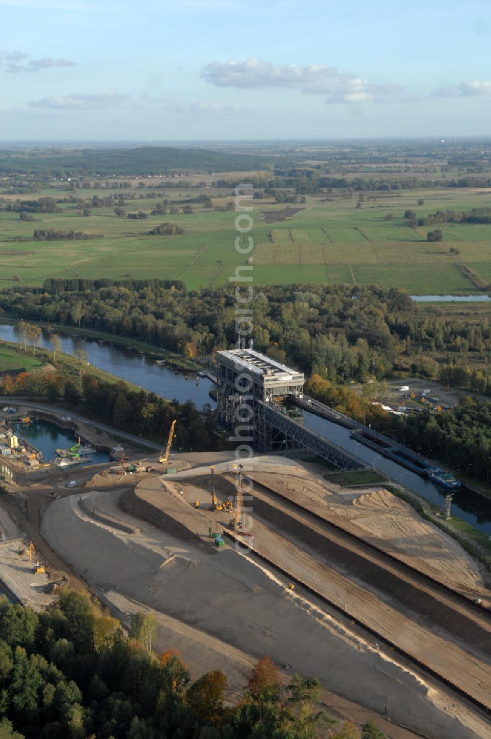 Niederfinow from the bird's eye view: Das Wasserstraßen-Neubauamt Berlin den Bauauftrag für den Neubau des Schiffshebewerkes Niederfinow Nord vergeben. Der Zuschlag wurde auf das Angebot der Bietergemeinschaft Neues Schiffshebewerk Niederfinow unter Federführung der Bilfinger Berger AG erteilt. Der Bietergemeinschaft gehören weiter: die DSD Brückenbau GmbH, die Johann Bunte Bauunternehmung GmbH & Co. KG und die Siemag GmbH an. Die geplante Bauzeit für das neue Schiffshebewerk beträgt fünf Jahre, die Baukosten für die Gesamtanlage liegen bei rd. 285 Mio. Euro und werden durch den Bund finanziert. Seit Mitte Februar 2009 wird die Baugrubenumschließung für das neue Schiffshebewerk hergestellt. Es werden 217 Träger und 214 Zwischenbohlen in den Baugrund eingebracht. Die Träger haben eine Länge von ca. 22m und wiegen einzeln etwa 5,7 Tonnen. Die Rüttelarbeiten für die Baugrube werden voraussichtlich bis Ende April andauern.Mit einem Investitionsvolumen von rd. 285. Mio € entsteht in Niederfinow bis zum Jahr 2014 ein neues Schiffshebewerk der europäischen Wasserstraßenklasse V. Der Neubau ist dringend erforderlich, weil das alte Schiffshebewerk aus dem Jahr 1934 bald das Ende seiner Lebensdauer erreicht hat. Um die Funktion der Havel-Oder-Wasserstraße aufrechtzuerhalten, muss es daher planmäßig durch einen Neubau ersetzt werden.