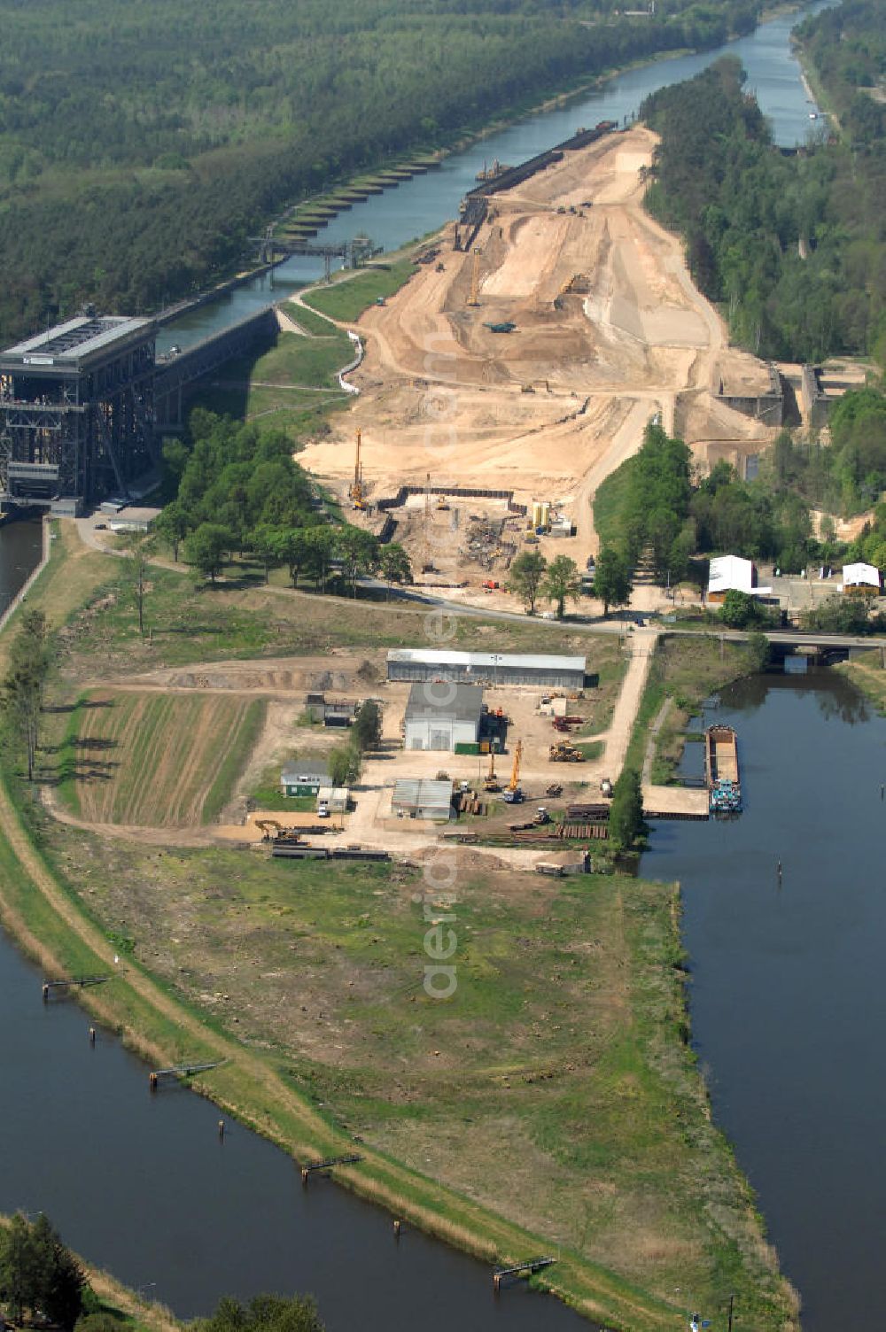 Aerial photograph NIEDERFINOW - Das Wasserstraßen-Neubauamt Berlin den Bauauftrag für den Neubau des Schiffshebewerkes Niederfinow Nord vergeben. Der Zuschlag wurde auf das Angebot der Bietergemeinschaft Neues Schiffshebewerk Niederfinow unter Federführung der Bilfinger Berger AG erteilt. Der Bietergemeinschaft gehören weiter: die DSD Brückenbau GmbH, die Johann Bunte Bauunternehmung GmbH & Co. KG und die Siemag GmbH an. Die geplante Bauzeit für das neue Schiffshebewerk beträgt fünf Jahre, die Baukosten für die Gesamtanlage liegen bei rd. 285 Mio. Euro und werden durch den Bund finanziert. Seit Mitte Februar 2009 wird die Baugrubenumschließung für das neue Schiffshebewerk hergestellt. Es werden 217 Träger und 214 Zwischenbohlen in den Baugrund eingebracht. Die Träger haben eine Länge von ca. 22m und wiegen einzeln etwa 5,7 Tonnen. Die Rüttelarbeiten für die Baugrube werden voraussichtlich bis Ende April andauern.Mit einem Investitionsvolumen von rd. 285. Mio € entsteht in Niederfinow bis zum Jahr 2014 ein neues Schiffshebewerk der europäischen Wasserstraßenklasse V. Der Neubau ist dringend erforderlich, weil das alte Schiffshebewerk aus dem Jahr 1934 bald das Ende seiner Lebensdauer erreicht hat. Um die Funktion der Havel-Oder-Wasserstraße aufrechtzuerhalten, muss es daher planmäßig durch einen Neubau ersetzt werden.